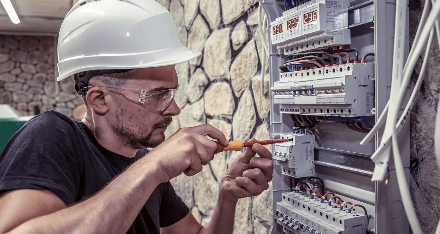 Técnico executando serviço em painel elétrico